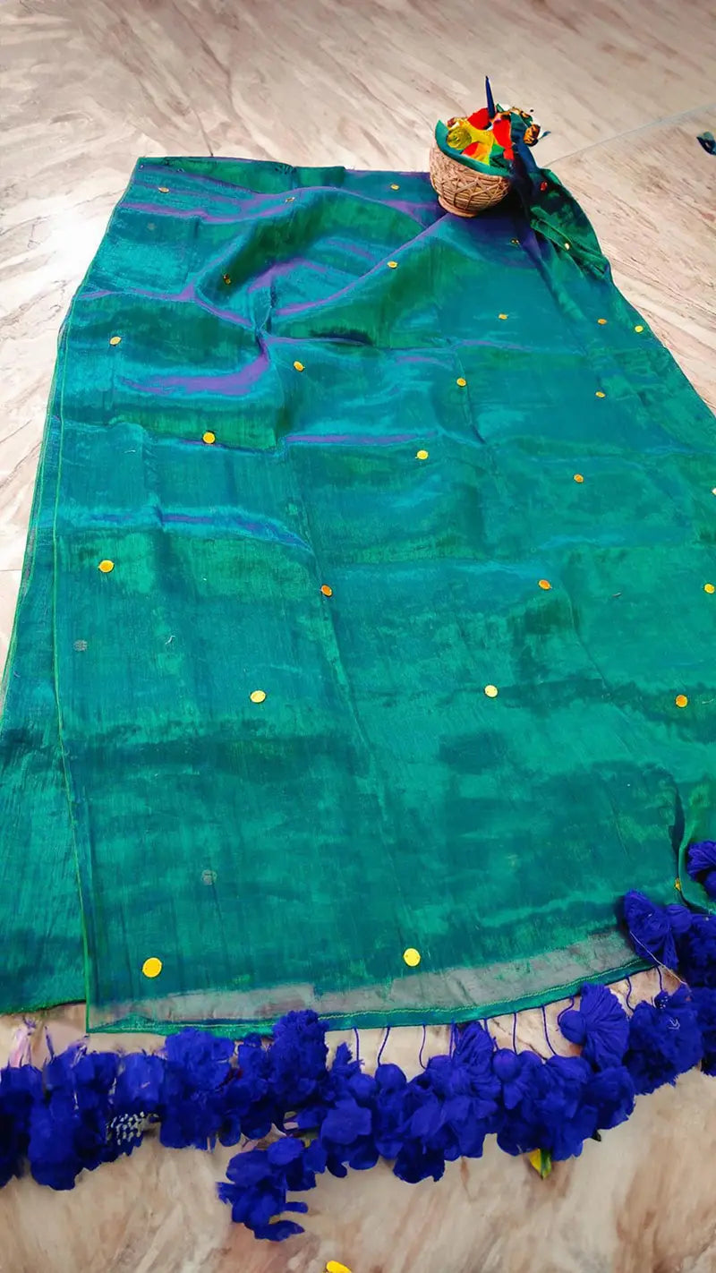 Green saree with blue pompom tassels on a wooden floor