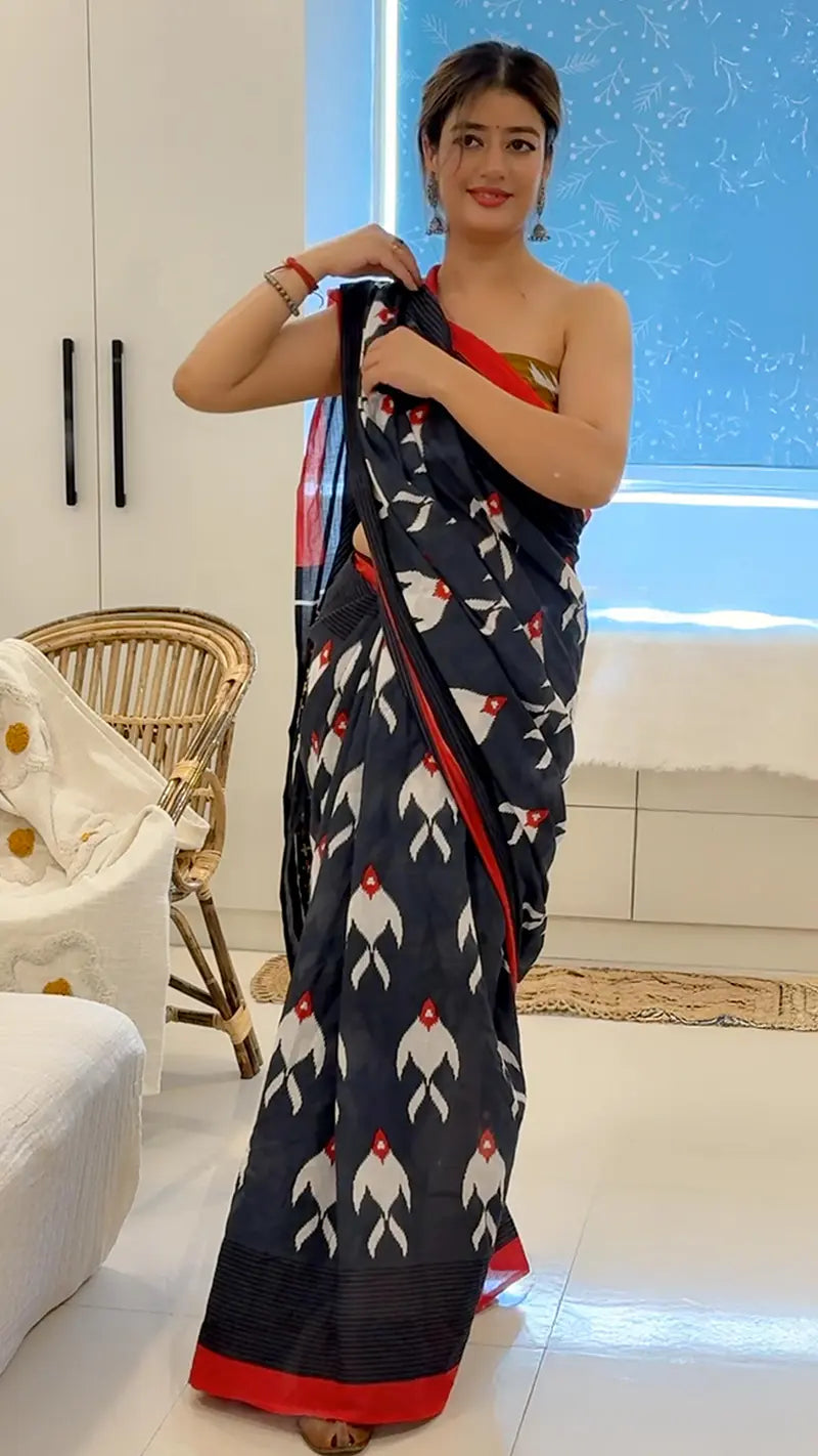 Woman holding a navy blue saree with white patterns in a modern living room.