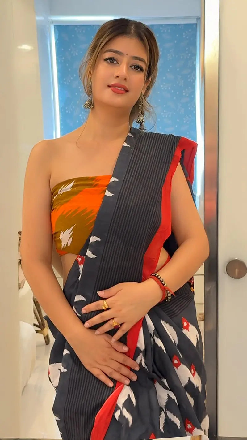 Woman wearing a traditional saree with a colorful pattern indoors.