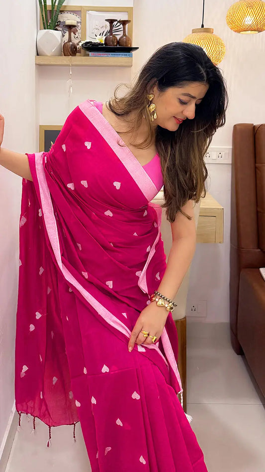 Woman wearing a pink soft cotton  saree with heart embroidery in an indoor setting.