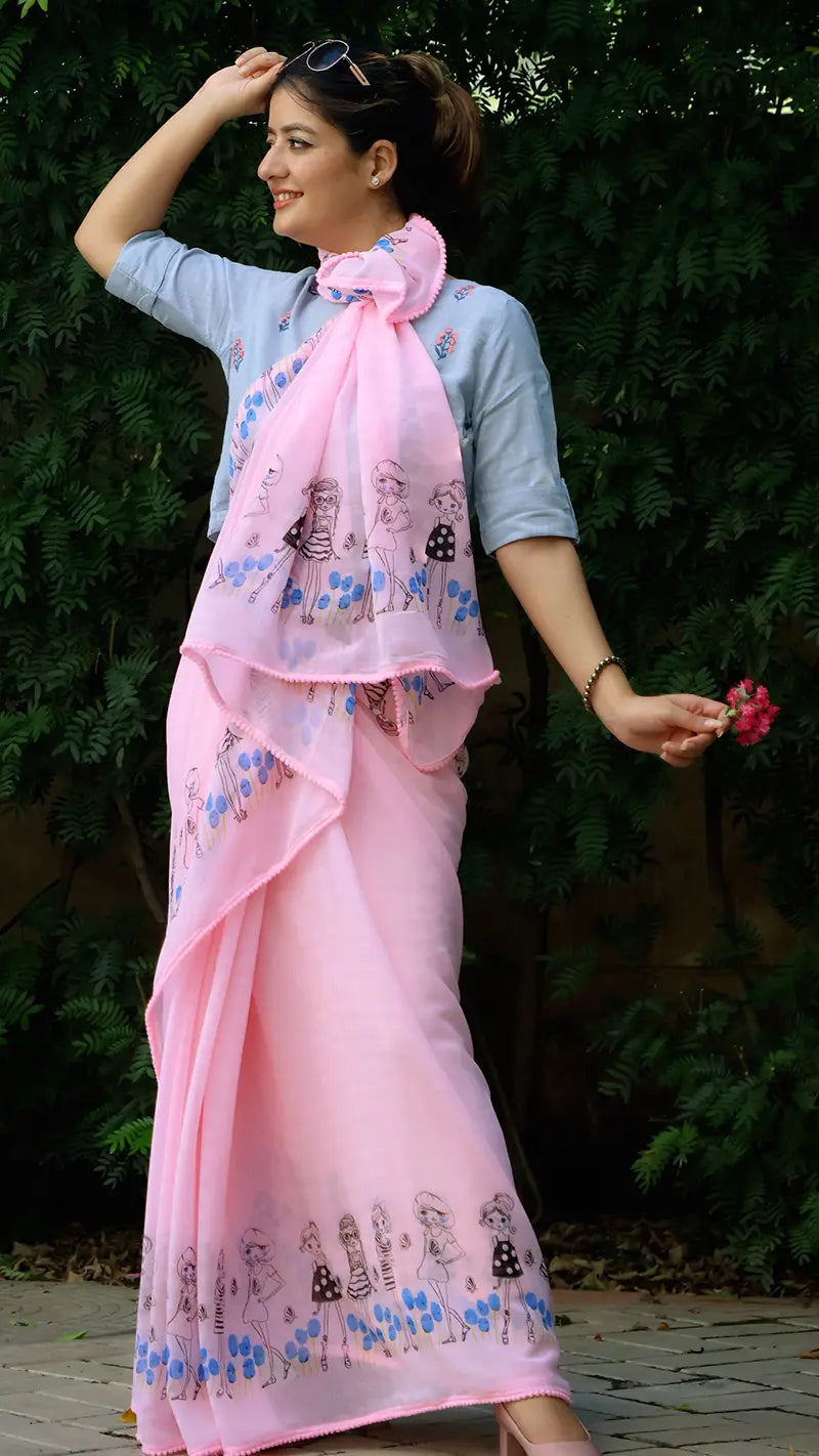 Woman wearing a pink chiffon saree with floral patterns against a green foliage background
