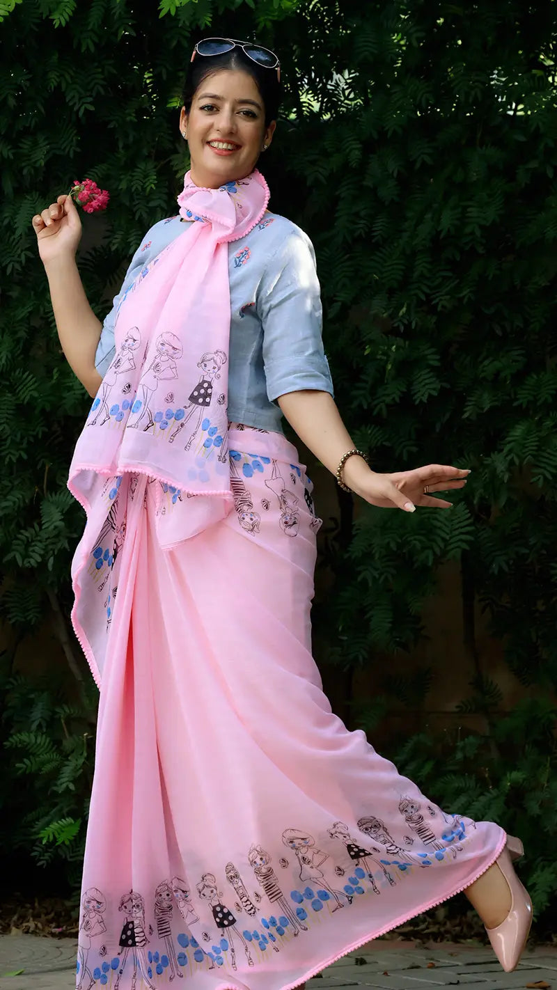 Woman wearing a pink saree with a blue blouse against a green background