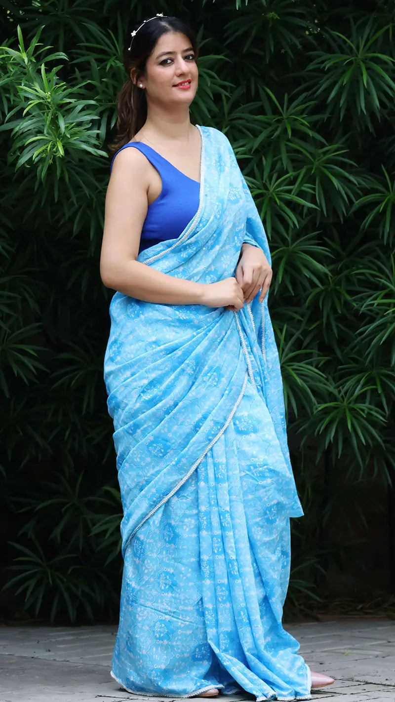Woman wearing a blue chanderi saree with a green leafy background