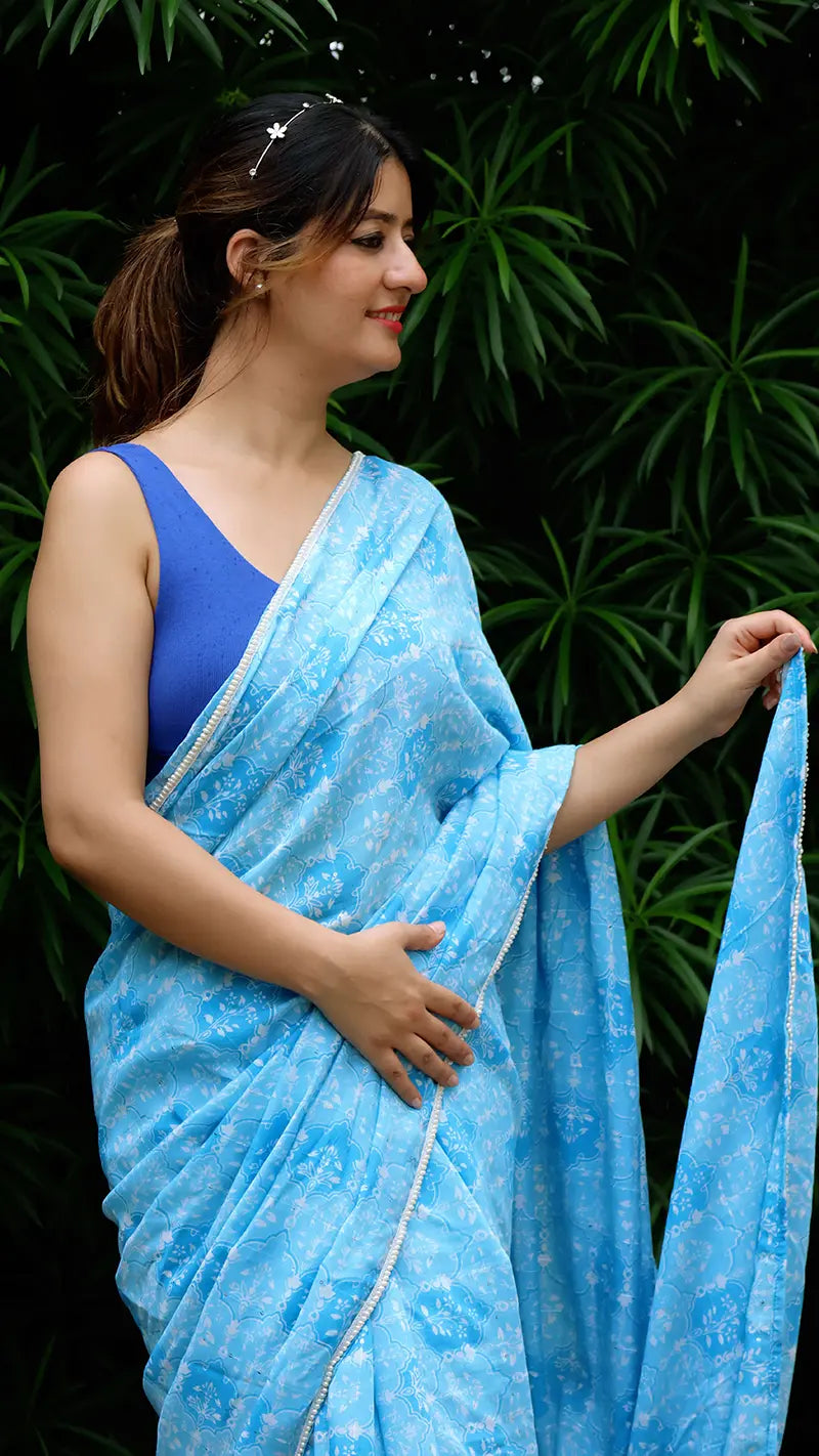 Woman wearing a blue chanderi saree with a green leafy background