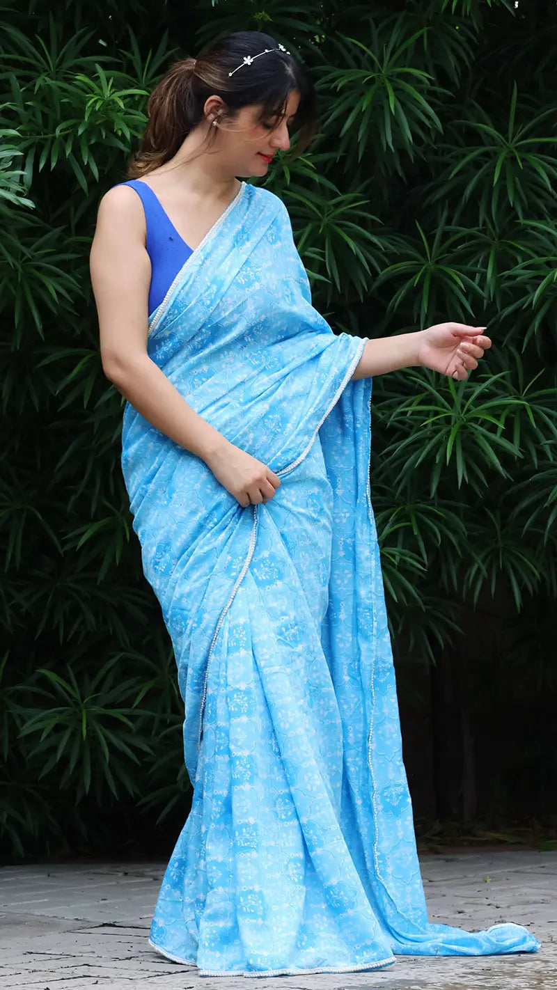 Woman wearing a light blue saree with a dark background