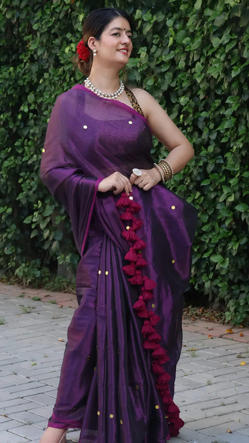 Woman wearing a purple tissue saree with a green leafy background