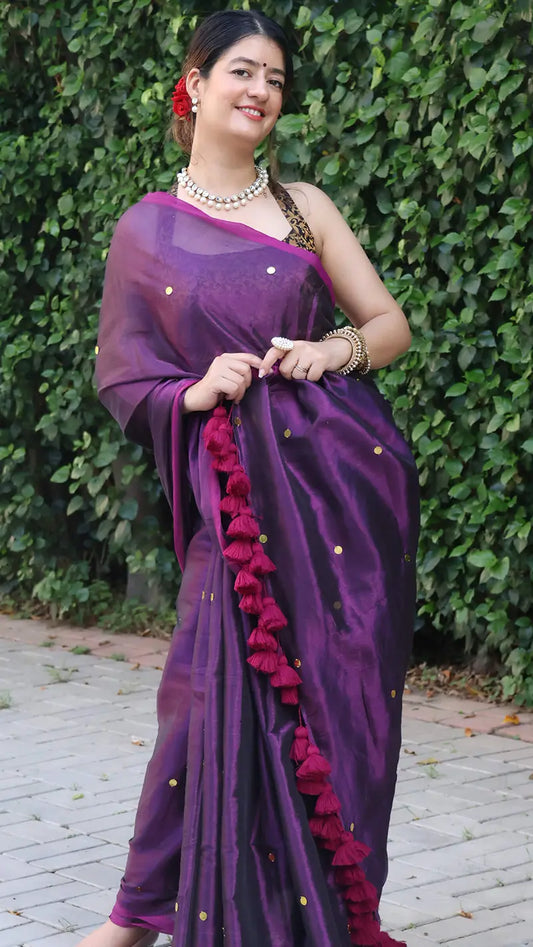 Woman wearing a purple saree with a green leafy background