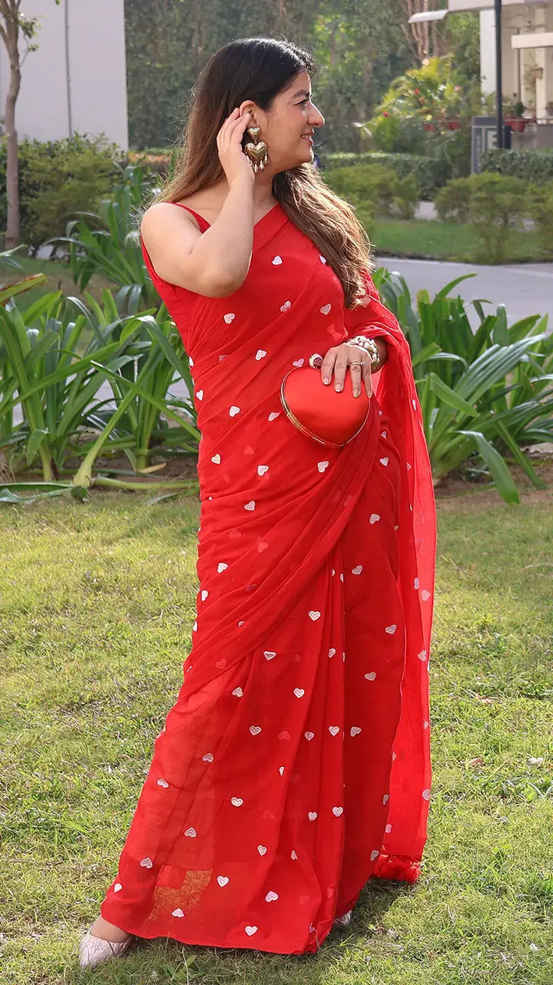 Woman wearing a red mul cotton saree with white embroidered hearts in an outdoor setting