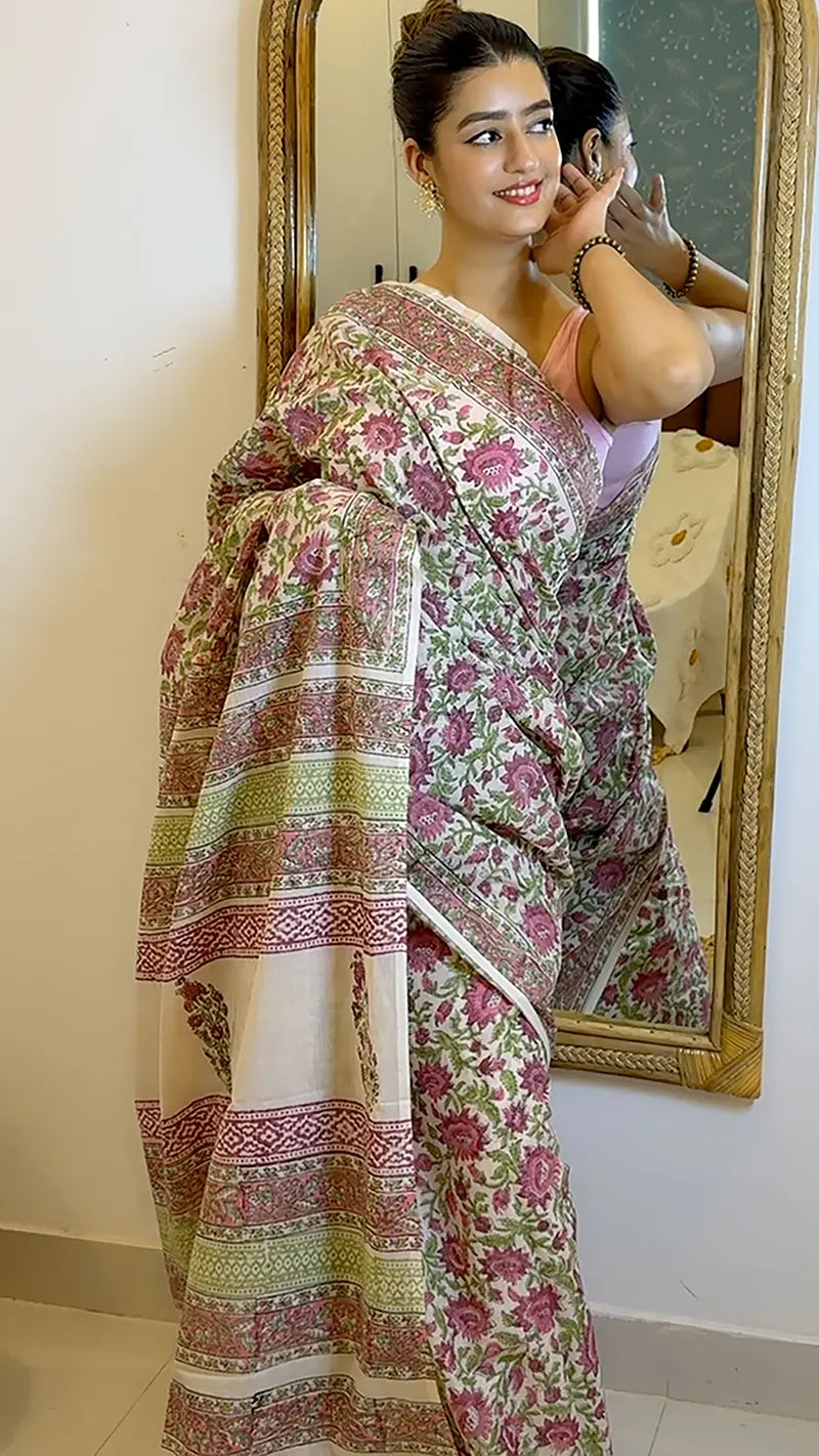 Woman wearing a floral saree in front of a mirror