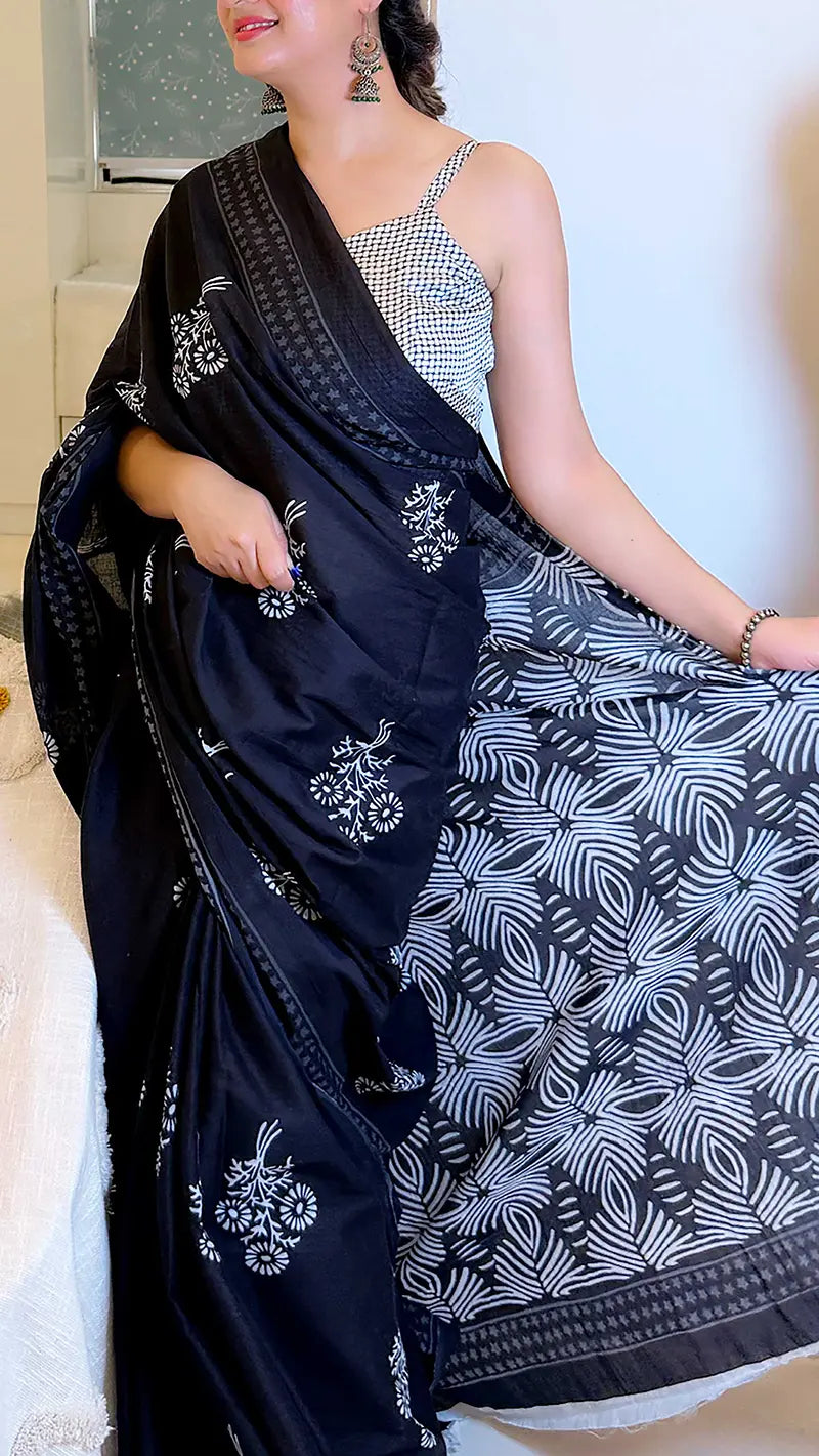 Woman wearing a black saree with white patterns and a silver blouse.