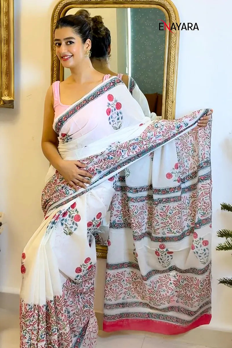 Woman holding a floral saree in front of a mirror with 'ENAYARA' branding.