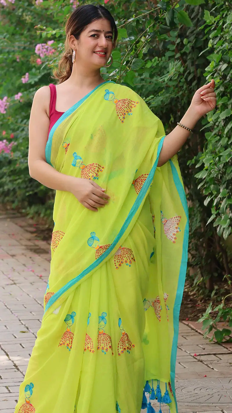 Woman wearing a bright green saree with a blue border outdoors.