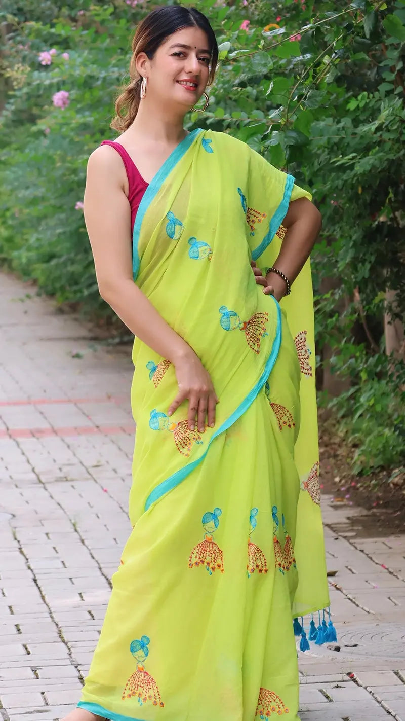 Woman wearing a bright green mul cotton saree with blue border in an outdoor setting