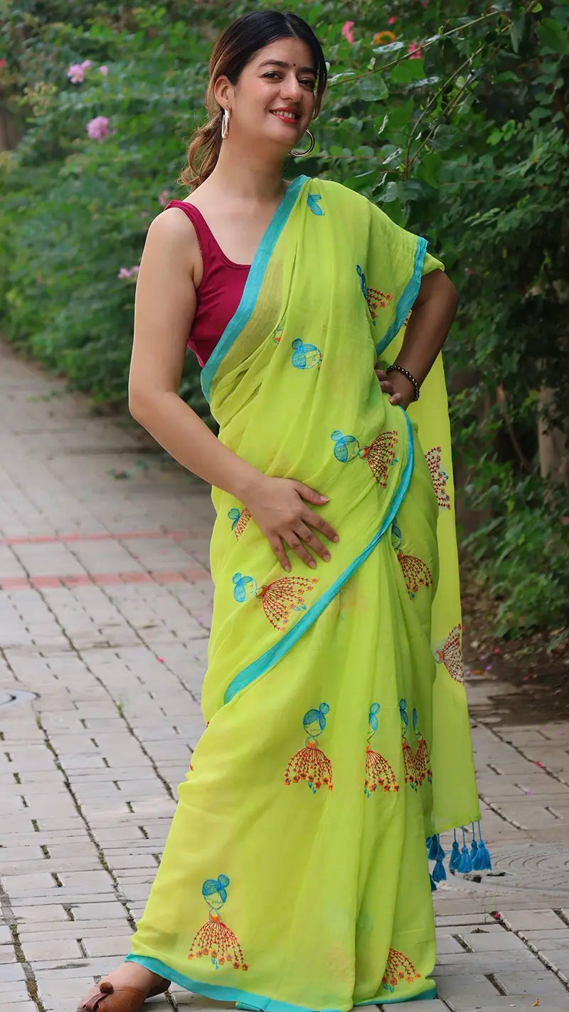 Woman wearing a bright green mul cotton saree with embroidered dolls in an outdoor setting