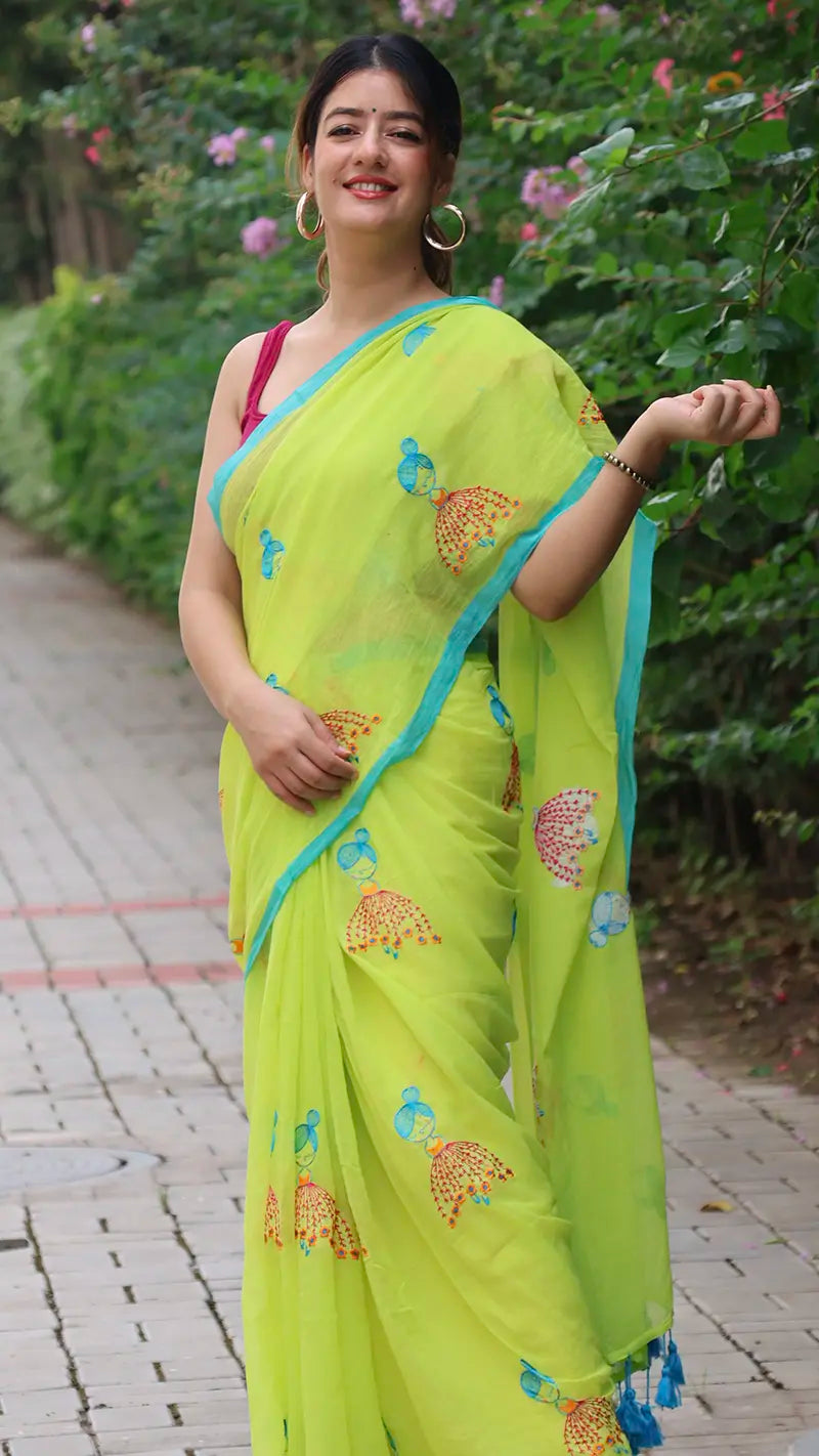 Woman wearing a bright green mul cotton saree with embroidered patterns outdoors.