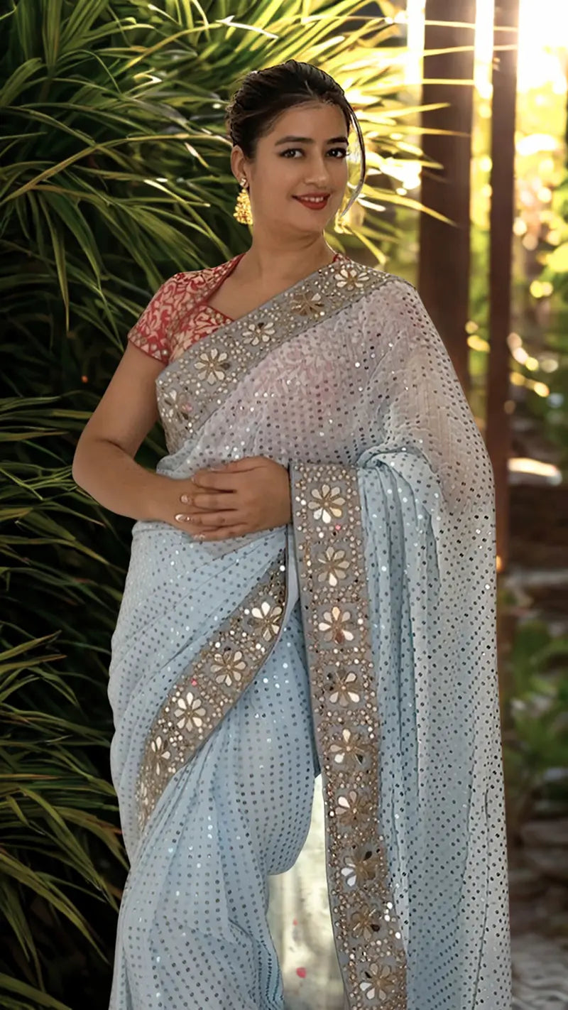 Woman wearing a Sequin Georgette Saree With Heavy Mirror Work Border against a natural background