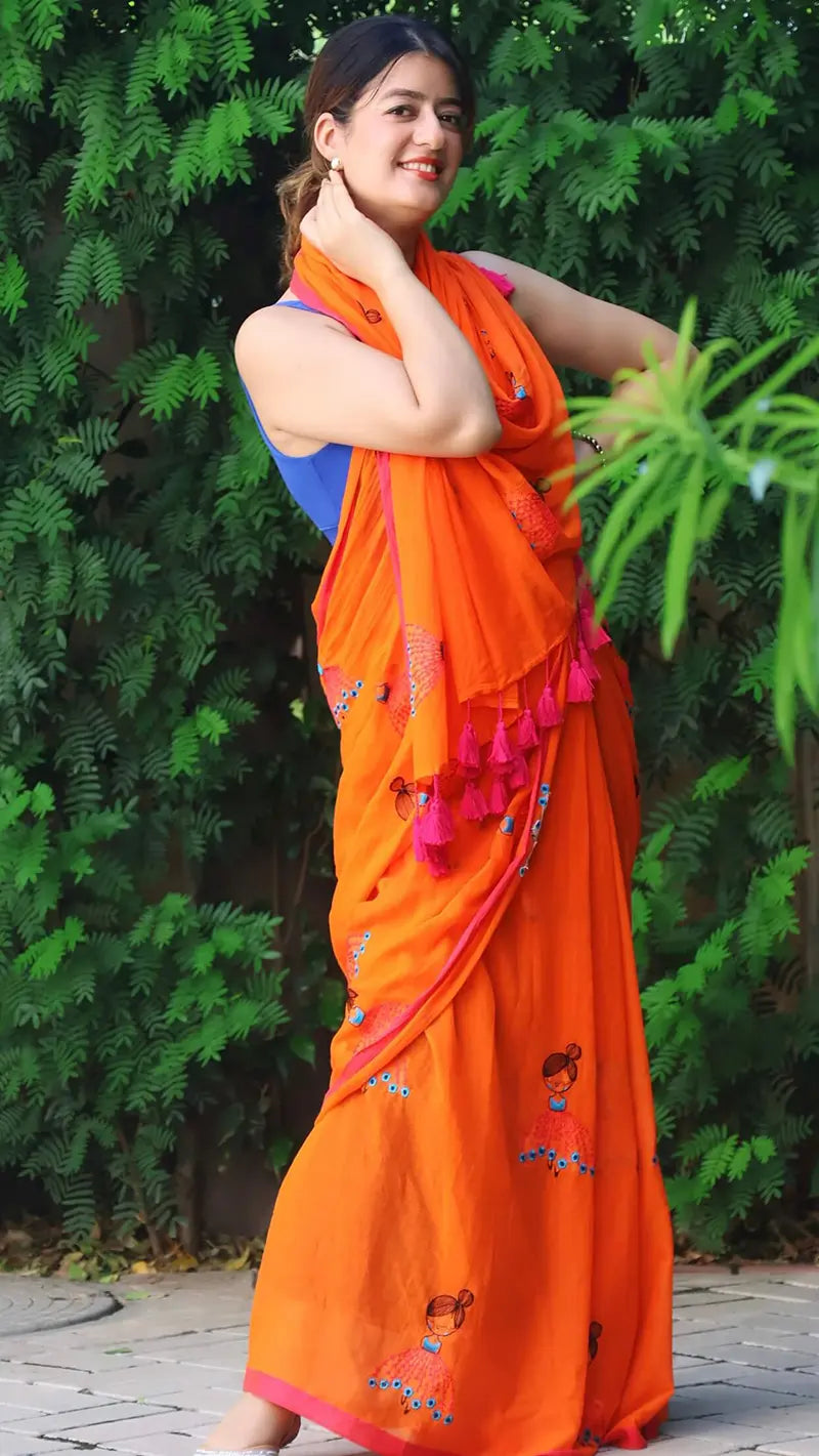 Woman wearing an embroidered orange mul cotton saree with large tassels