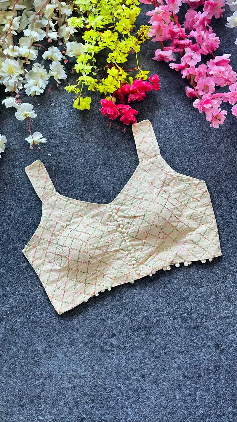 Beige lace blouse on a dark surface with colorful flowers in the background