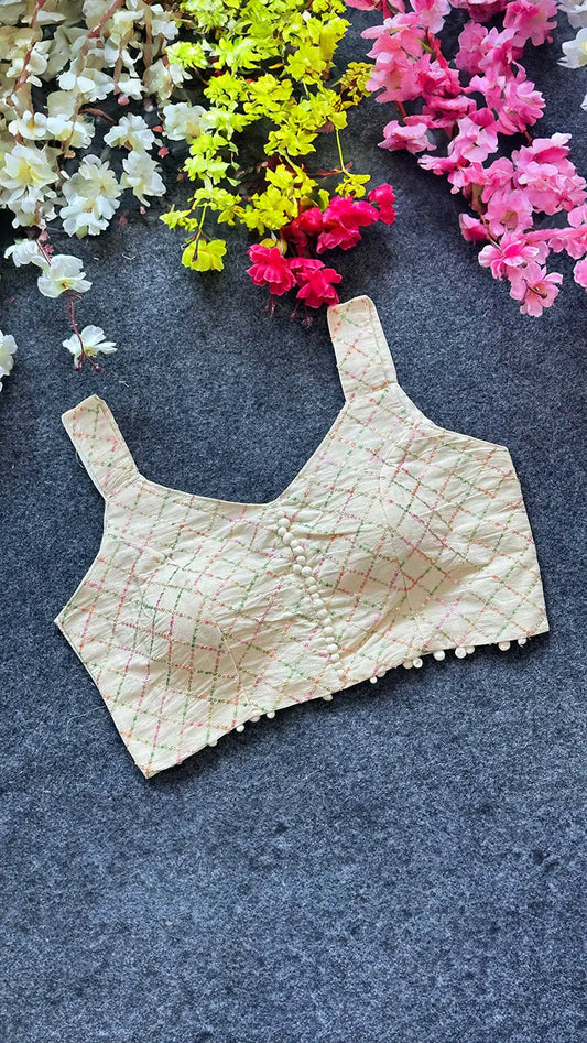 Beige lace blouse on a dark surface with colorful flowers in the background