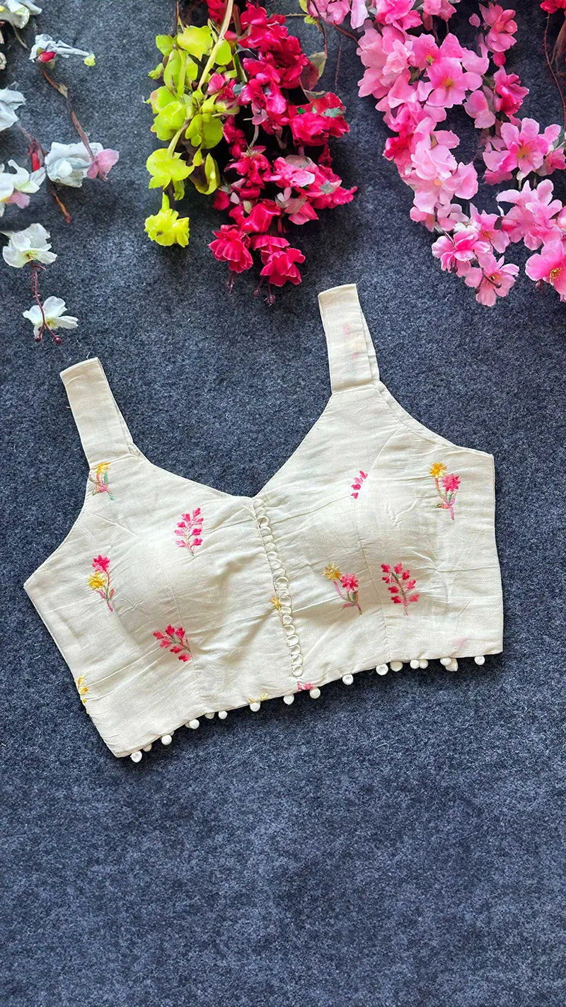 White embroidered bouse on a dark textured surface with flowers around.