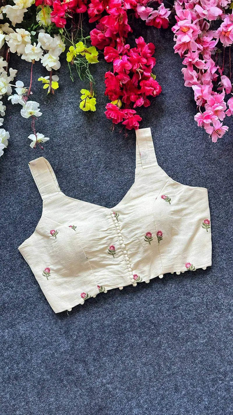 Beige blouse with floral embroidery on a dark surface with flowers in the background