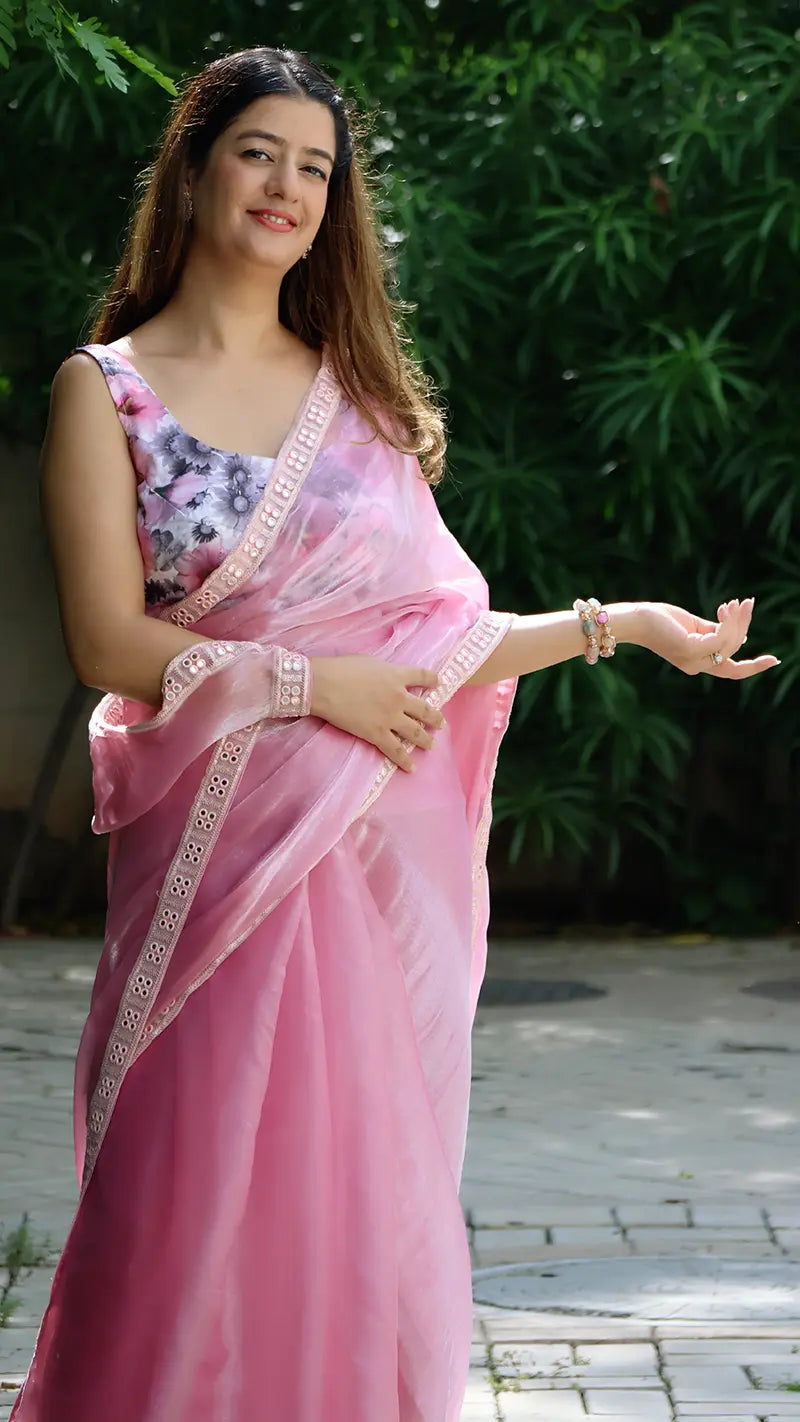 Woman in a pink jimmy choo saree standing outdoors with greenery in the background