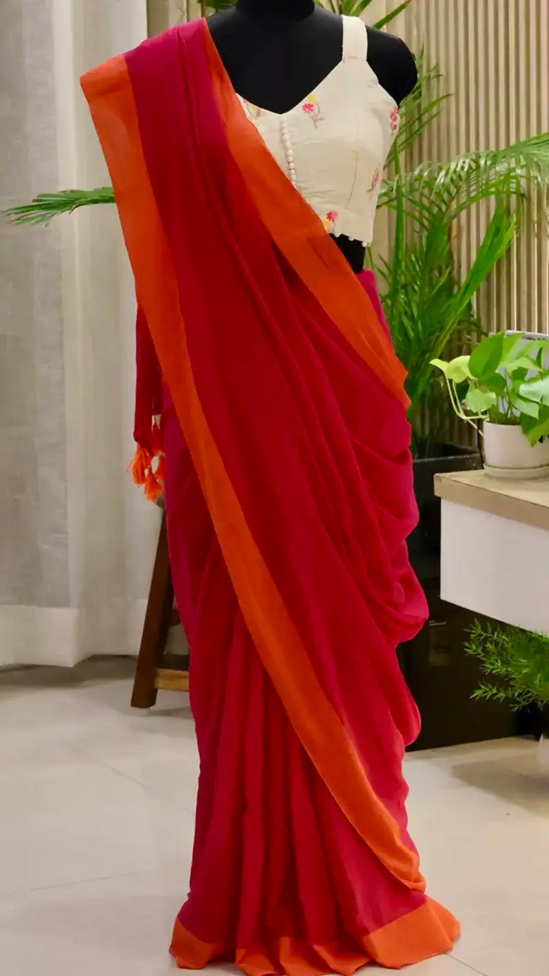 Red and orange saree draped over a mannequin with a plant in the background