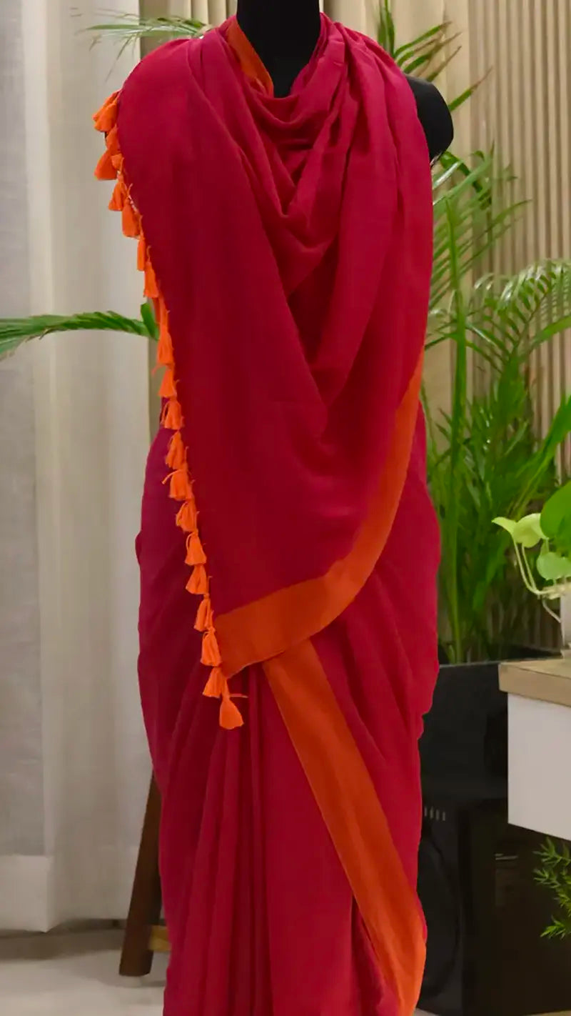 Red and orange saree with tassels on a mannequin against a neutral background