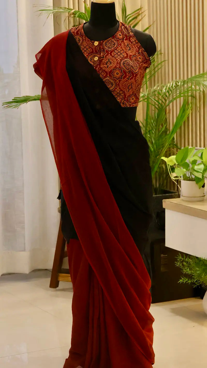 Black saree with red blouse draped over a mannequin against a neutral background