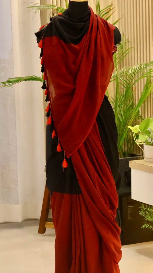 Red and black saree with tassels on a mannequin against a neutral background