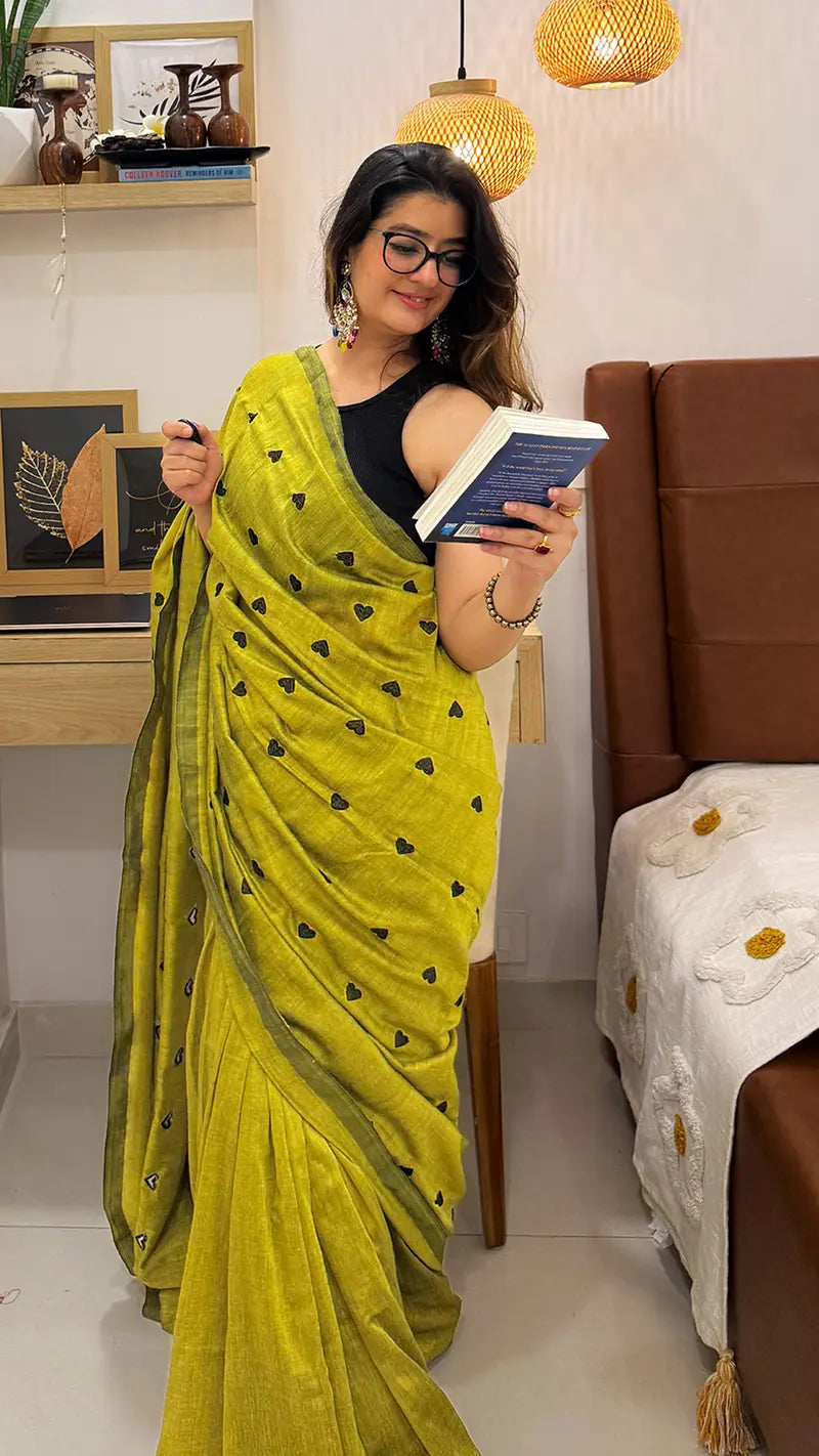 Woman in a soft cotton saree holding a book in a living room setting