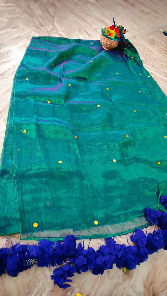 Green saree with blue pompom tassels on a wooden floor