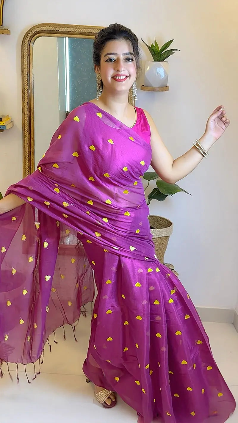 Woman wearing a magenta saree with yellow patterns in a room.
