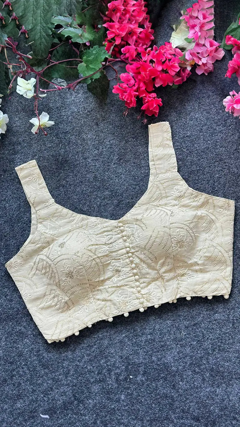 Beige lace blouse on a dark surface with pink flowers in the background